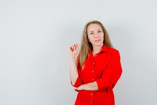 Blonde lady looking at camera in red shirt and looking pensive ,