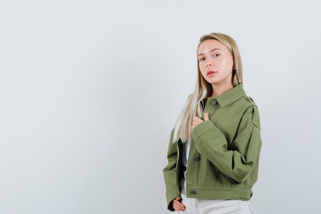 Blonde lady posing while standing in jacket, pants and looking confident. front view.