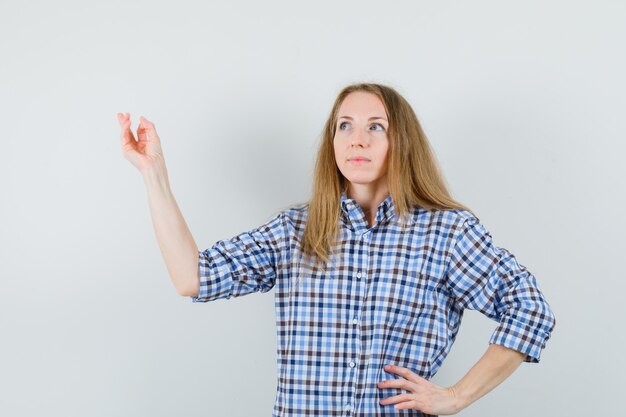 Blonde lady raising arm while looking up in shirt and looking hopeful ,