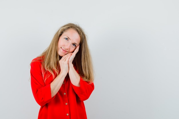 Blonde lady in red shirt leaning on palms as pillow and looking cute ,