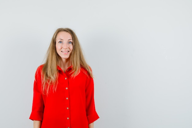 Blonde lady in red shirt looking at camera and looking astonished ,