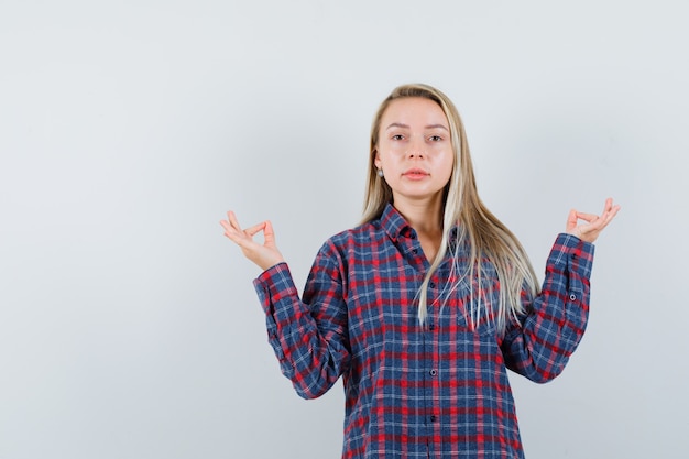 Blonde lady showing meditation gesture in casual shirt and looking confident. front view.