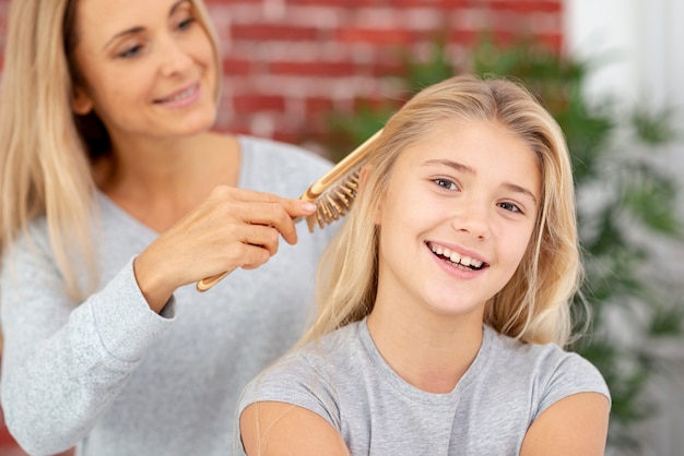 Blonde mother combing daughter hair