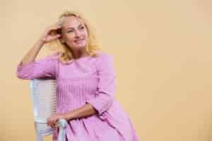 Free photo blonde senior woman wearing a pink dress with copy space