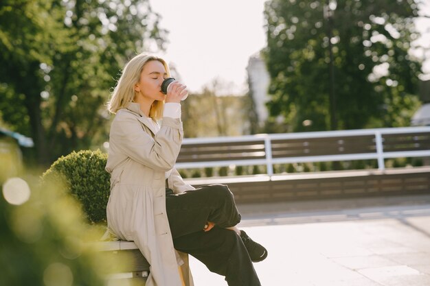 Blonde in a summer city with cup of coffee