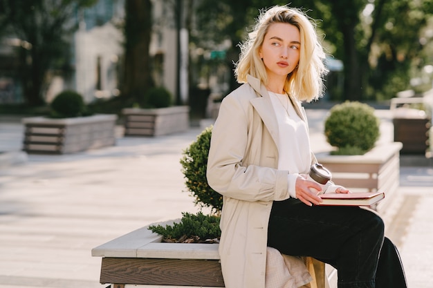 Blonde in a summer city with cup of coffee