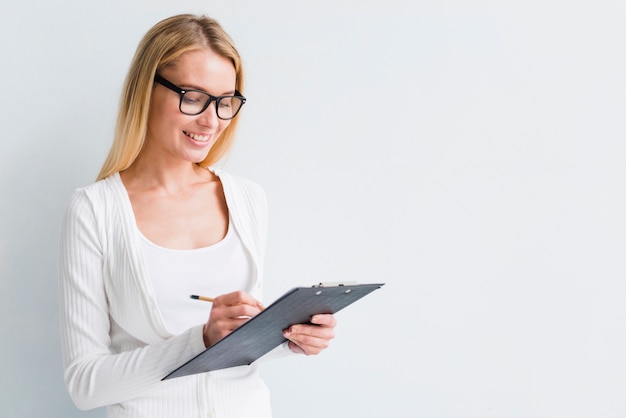 Blonde with glasses writing on clipboard