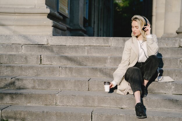 Blonde with headphones sitting on a stairs