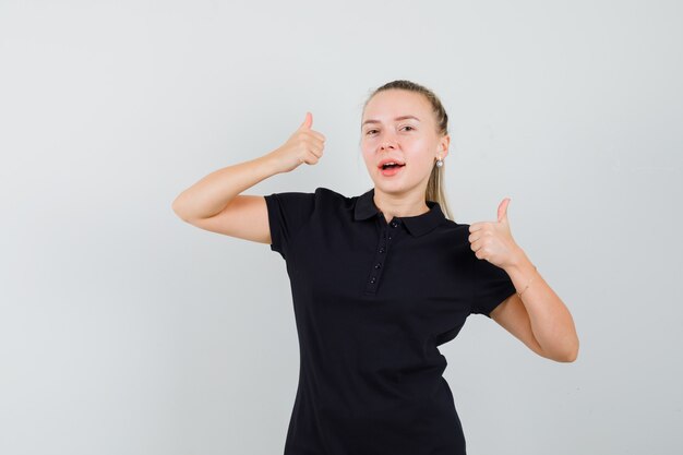 Blonde woman in black t-shirt showing thumbs up and looking optimistic