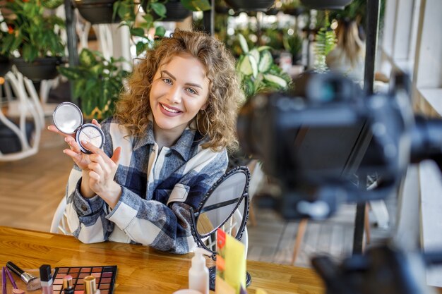 Blonde woman blogger is showing how to make up and use cosmetics