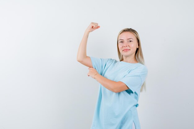 Blonde woman in blue t-shirt showing muscles and looking powerful