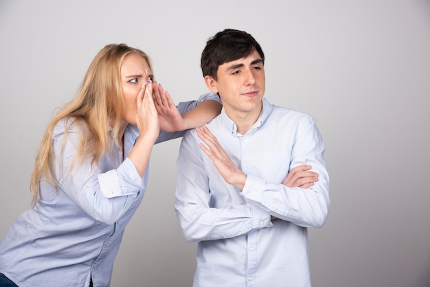 Blonde woman calling a brunnete guy model on gray background