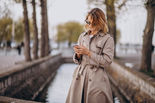 Free photo blonde woman in coat outside in park