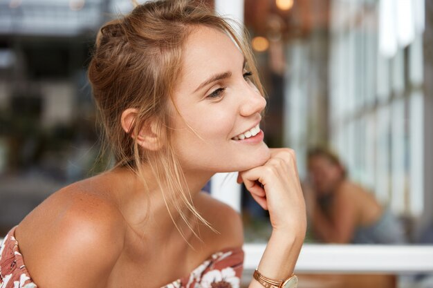 Blonde woman in floral dress in cafe