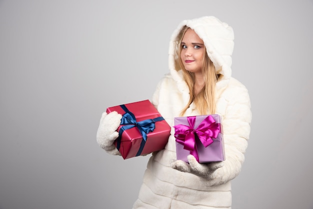 Blonde woman happily showing gift boxes.