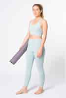 Free photo blonde woman holding yoga mat in blue sports bra and leggings full body