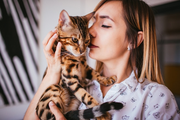 Free photo blonde woman holds a bengal cat