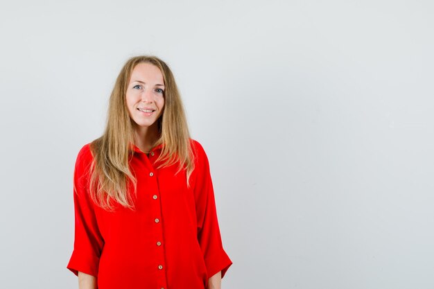 Blonde woman looking at camera in red shirt and looking jovial.