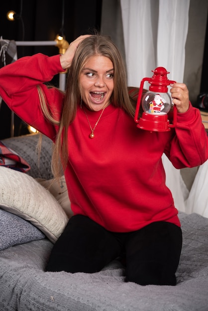 Free Photo blonde woman in pajamas happily looking at christmas lamp. 