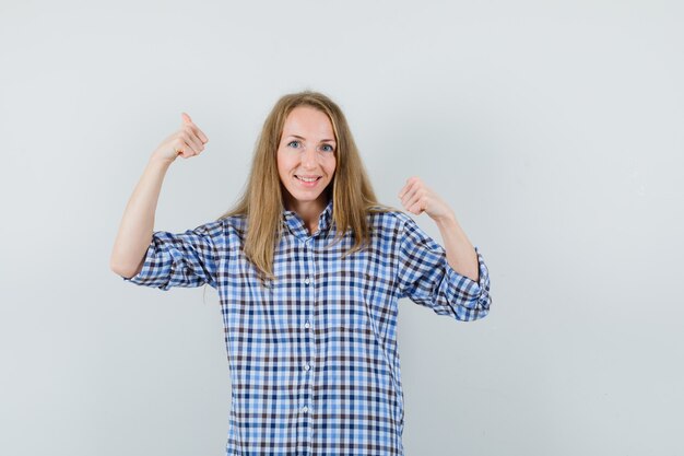 Blonde woman in shirt showing double thumbs up and looking happy ,