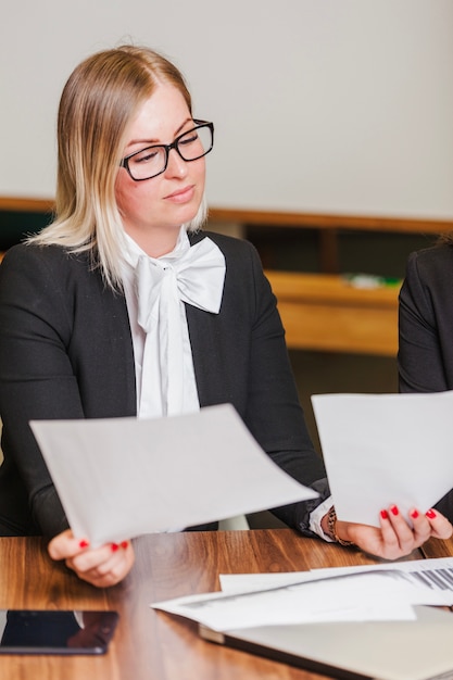 Blonde woman sitting at desk holding sheets