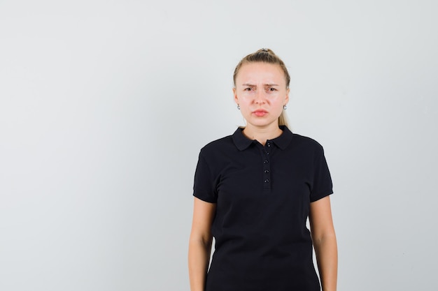 Free photo blonde woman standing straight in black t-shirt and looking confused