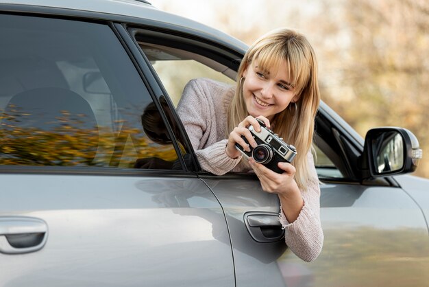 Blonde woman taking pictures from car