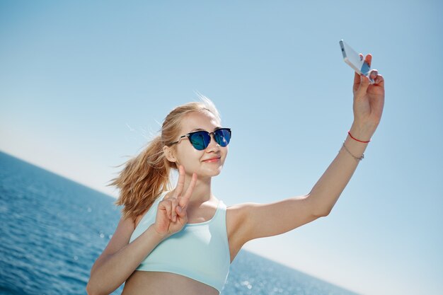 Blonde woman taking selfie on the beach