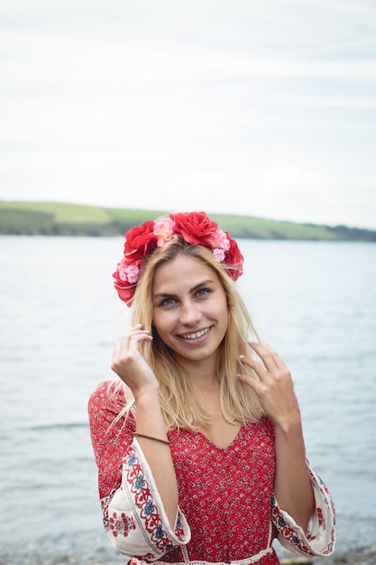 Blonde woman wearing a flower tiara standing near a river