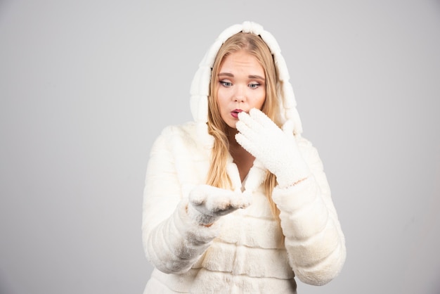 Blonde woman in winter outfit looking at her hand.