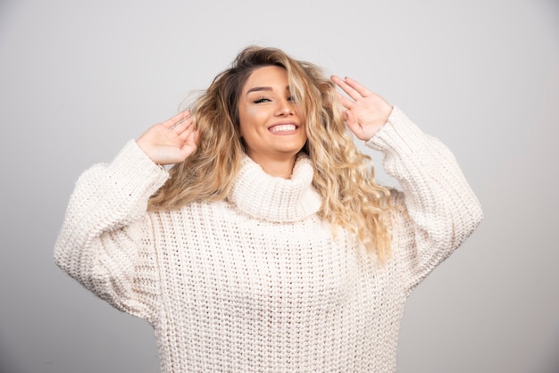 Blonde woman in winter outfit playing with her hair. 