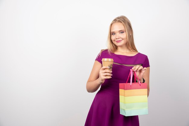 Blonde woman with cup of coffee and bag posing. High quality photo