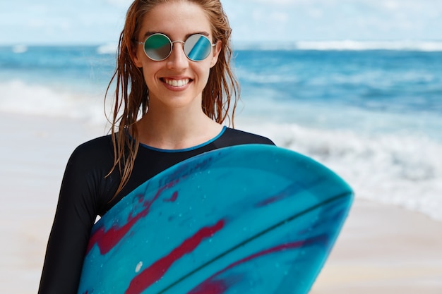 Blonde woman with surfboard on beach