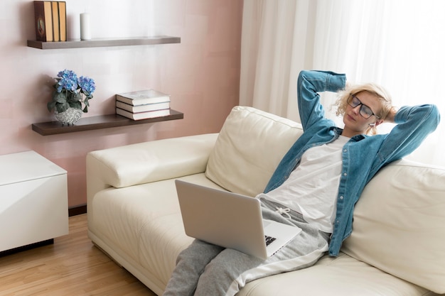 Blonde woman working on laptop and sitting on couch