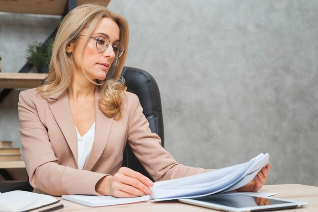 Blonde young businesswoman reading the documents at workplace