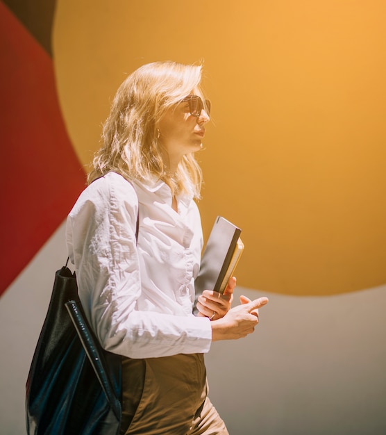 Blonde young businesswoman walking with diaries in hand