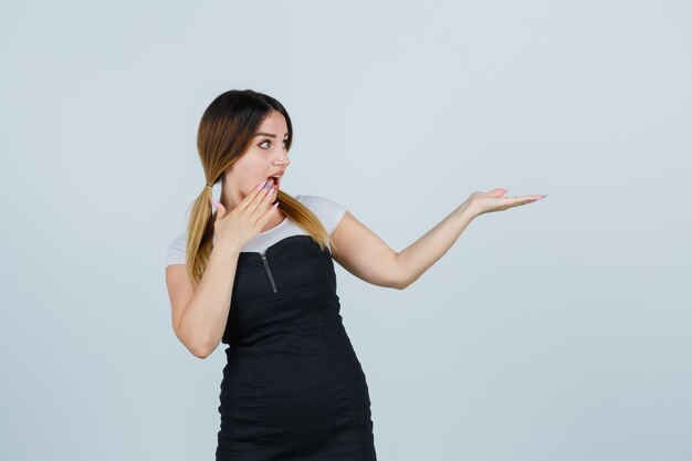 Blonde young lady in dress gesturing isolated