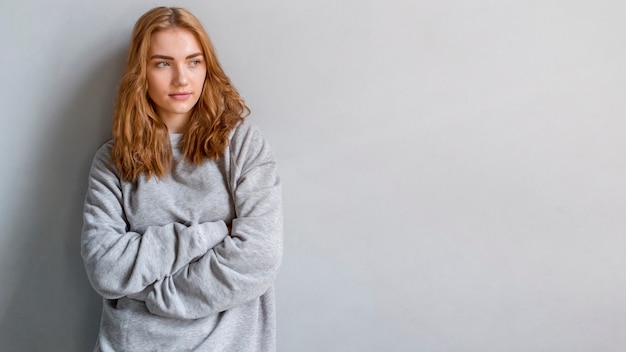 Blonde young woman against grey wall looking away