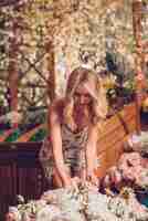 Free photo blonde young woman arranging the roses in the flower garden