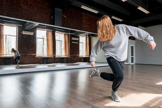 Free photo blonde young woman dancing against the mirror in the dance studio