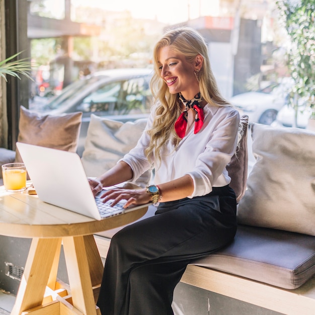 Blonde young woman sitting in the caf� using laptop