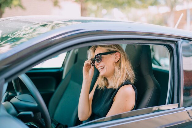 Blonde young woman sitting in the car laughing