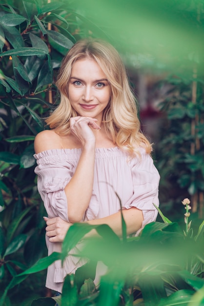 Blonde young woman standing in the garden looking at camera