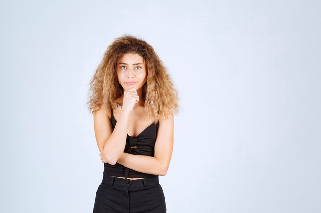 Blondie girl with curly hairs looks confused and lost. 