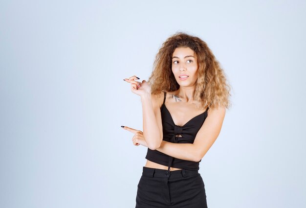 Blondie girl with curly hairs pointing to the left. 