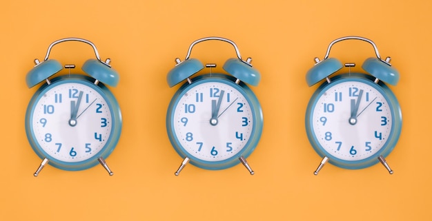 Blue alarm clocks on orange background isolated flat lay