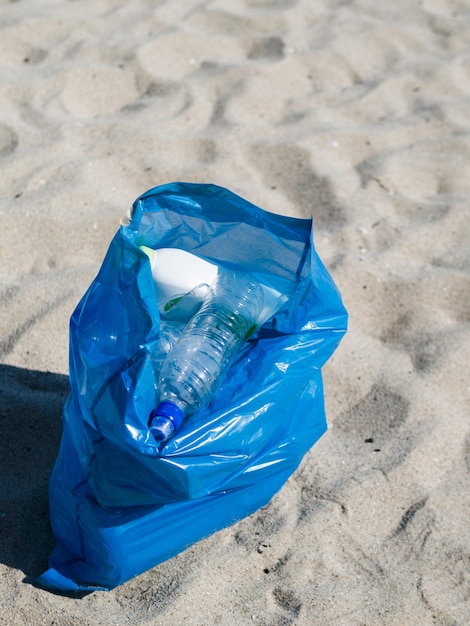 Free Photo blue bag of plastic garbage on sand at beach