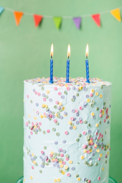 Blue birthday cake with lit candles