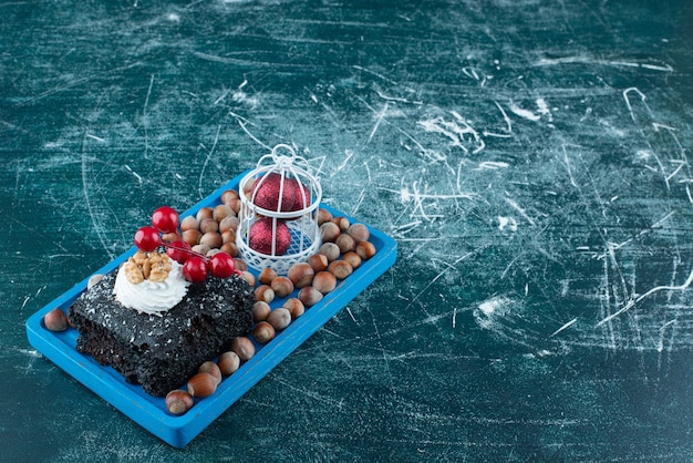 Free photo a blue board with a piece of chocolate cake and macadamia nuts. high quality photo