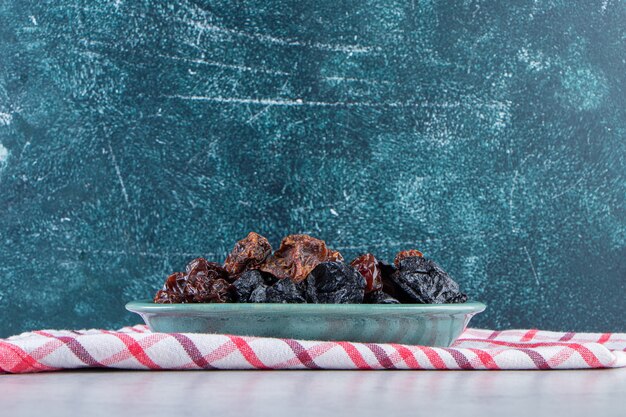 Free photo blue bowl of delicious dried dates on stone background.